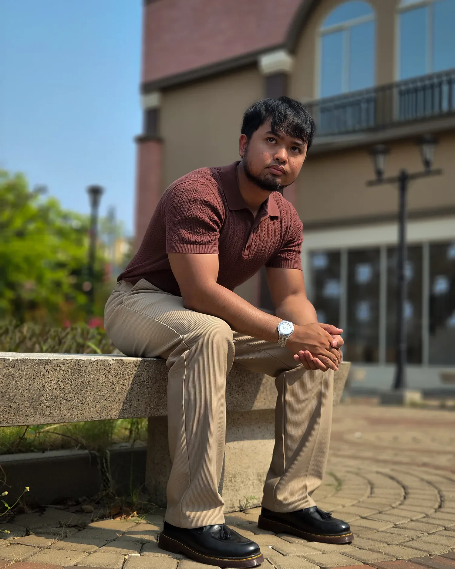 Pria mengenakan Mazly Signature Polo cokelat tua dalam pose duduk