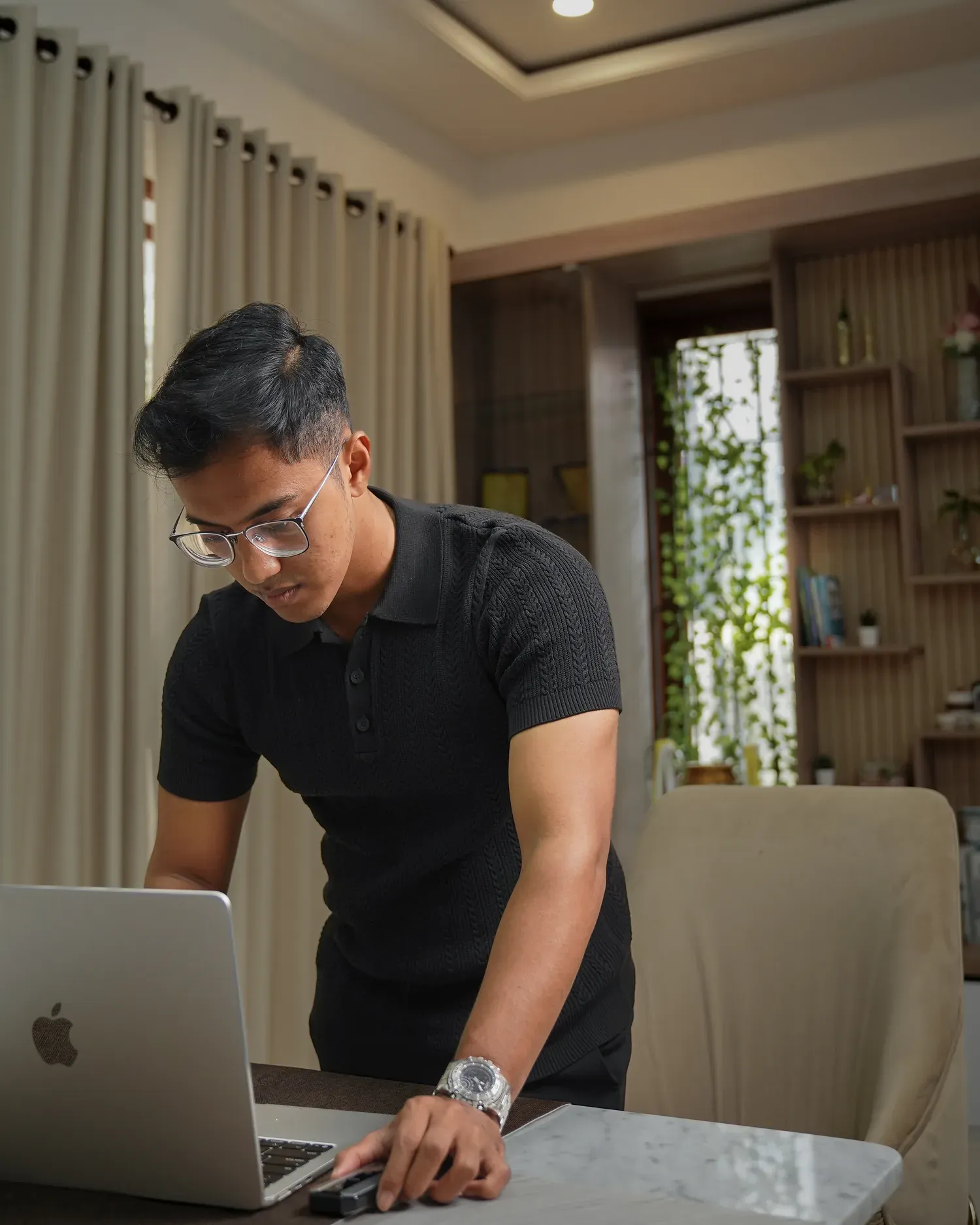 Pria mengenakan Mazly Signature Polo hitam saat bekerja dengan laptop di ruang kerja